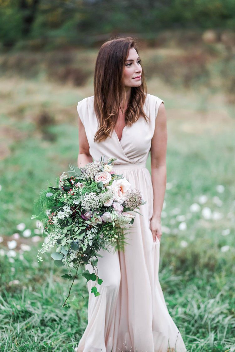 Bride in a meadow holding a soft garden bouquet